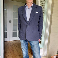 Photo of the upper body of a gentleman wearing a navy coloured sports jacket, in front of a doorway.