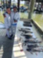 Husband and wife smiling next to a table of fish caught on a fishing charter in Lake Pontchartrain, Louisiana, including catfish and redfish.
