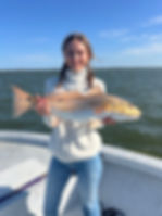 Woman smiling while holding a large redfish on a fishing charter in Lake Pontchartrain, Louisiana.