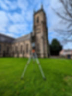 A laser scanner capturing detailed measurements of a historic church's exterior elevations.