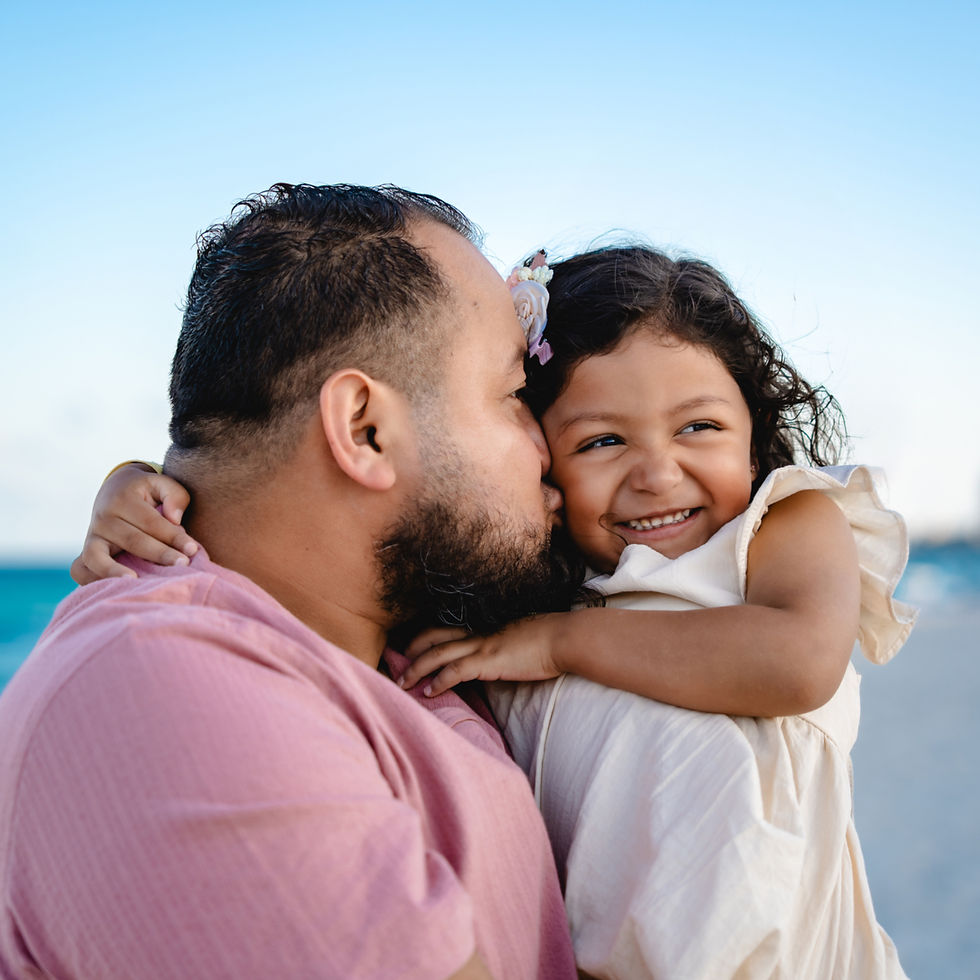 Father kissing daughter during a beach photoshoot in Cancun emotional family moment at Playa Delfines