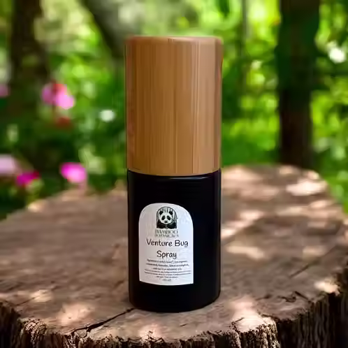 Eye-level view of a glass bottle of peppermint essential oil surrounded by fresh mint leaves on a wooden table