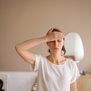 Young woman suffering from a tension headache holding her forehead at work