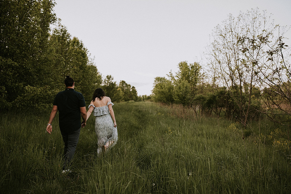 A couple holding hands and walking through tall grass