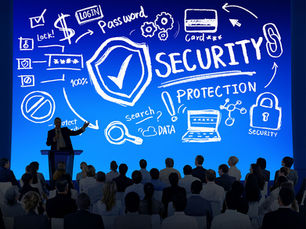 Audience watches a speaker on stage with a large blue background. White graphics show security concepts like protection, passwords, and locks.