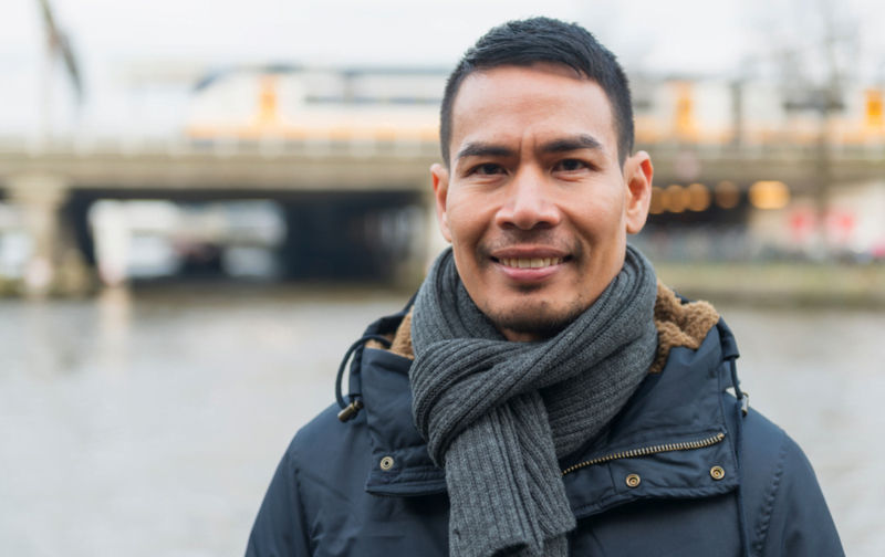 Man wearing a scarf smiling at camera outdoors