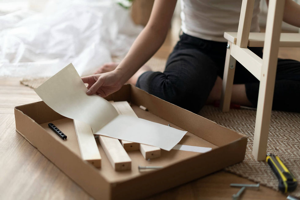 Woman assembling Ikea stool with box of loose parts on floor.