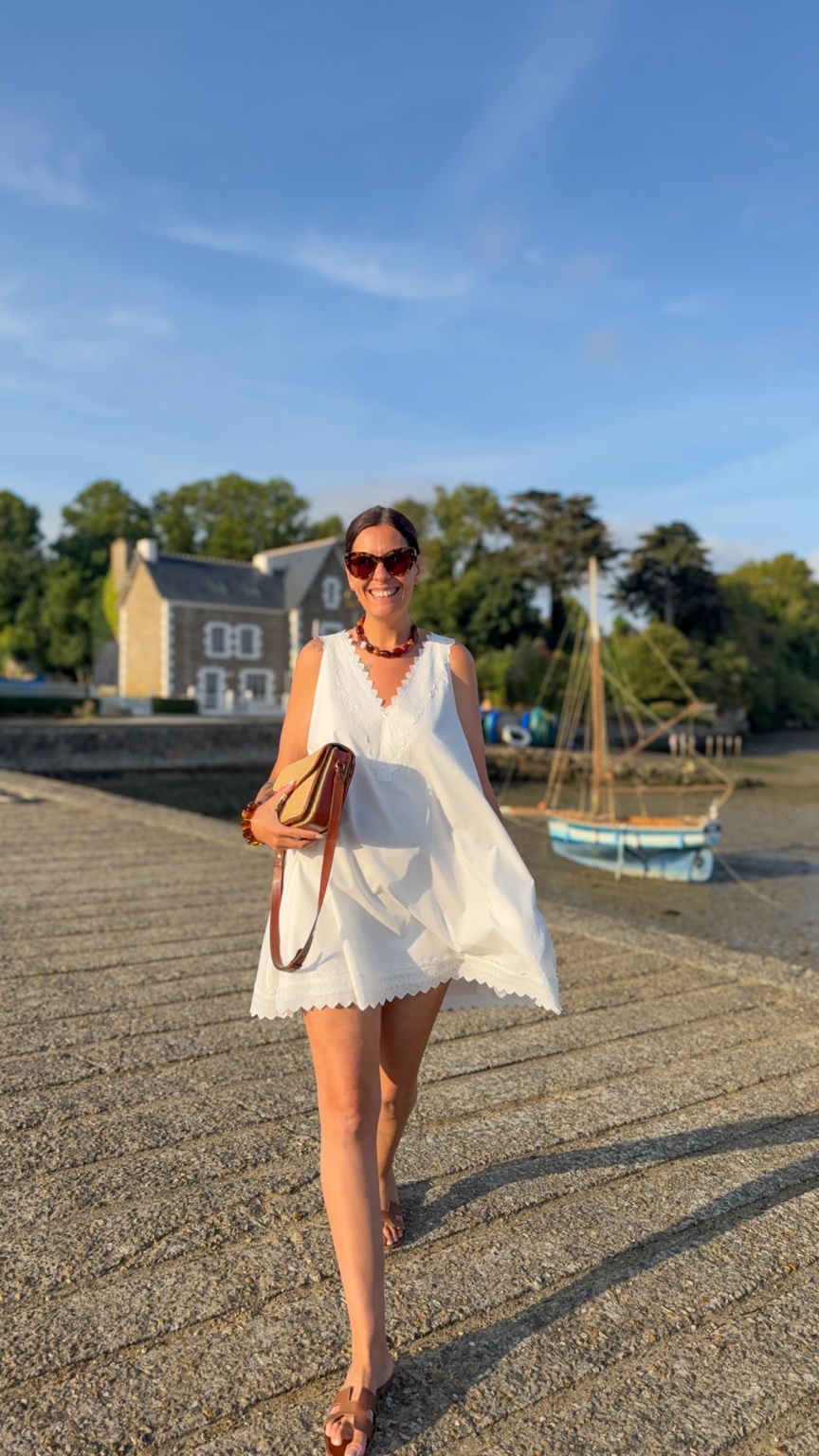 Jenny souriante en robe blanche au bord de l’eau