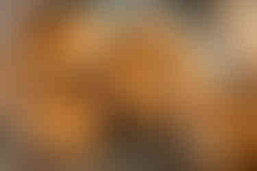 Brown macarons with Eiffel Tower and "Happy Holidays" text, filled with white cream, on a wooden surface, creating a festive, elegant mood.