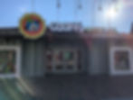 Goofy's Candy Co. storefront with striped walls, bright sun overhead, and a cheerful sign of Goofy. Sunny day with a playful ambiance. This is Disney Springs at Walt Disney World.