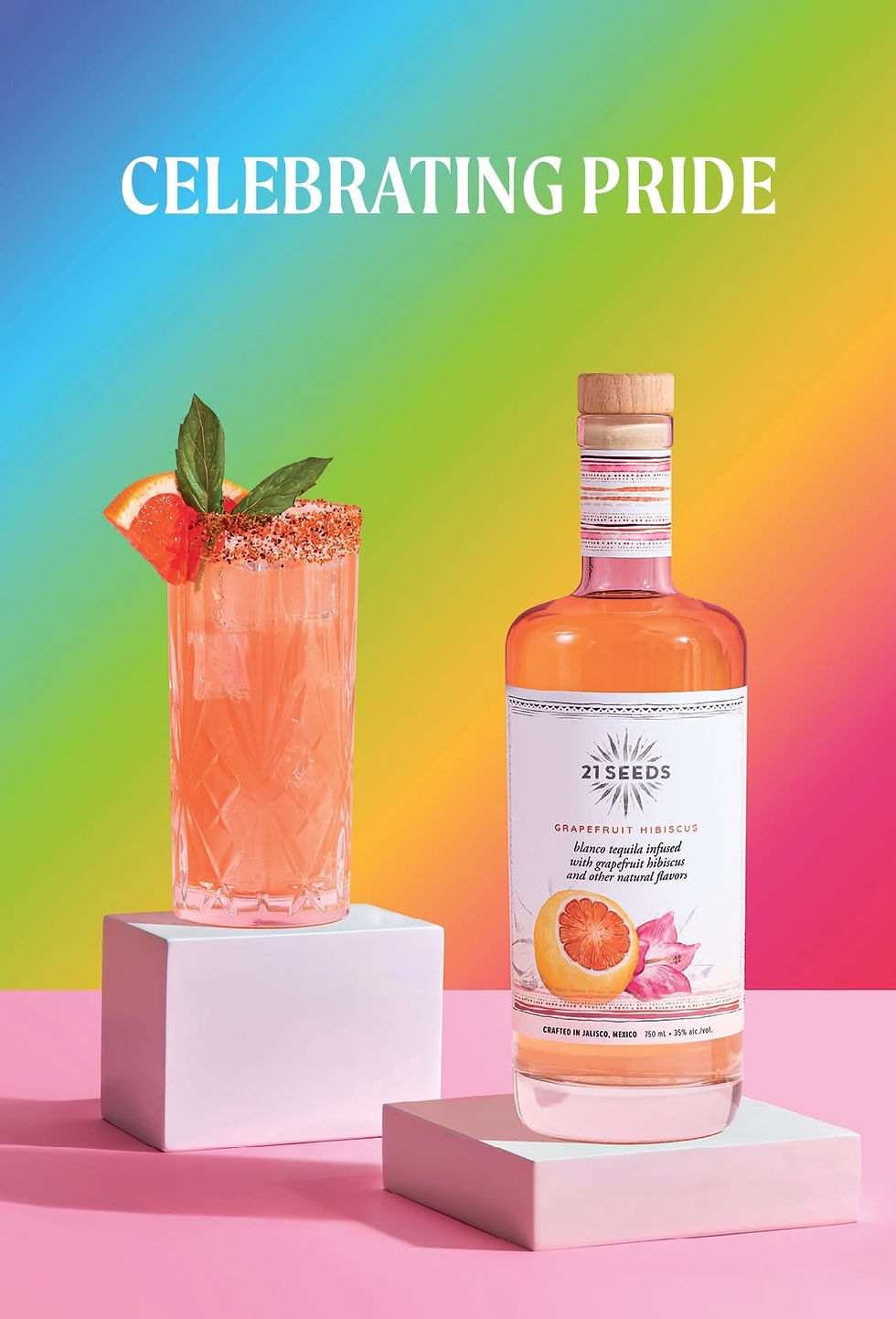 Bottle and cocktail of grapefruit hibiscus tequila on white pedestals. Gradient rainbow background, text "CELEBRATING PRIDE" above.