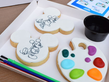 Cookies shaped like mouse heads, with drawings, on a tray with paintbrushes, palette cookie with colorful icing, and instructions.