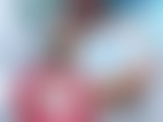 Three festive donuts with red, blue, and chocolate icing topped with colorful sprinkles and cream, on a tray with snowy decor and a toy truck.