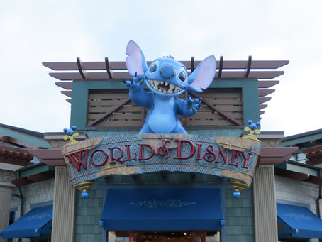 Blue Stitch statue atop World of Disney store entrance. Sign reads "World of Disney." Playful, colorful design with blue accents.