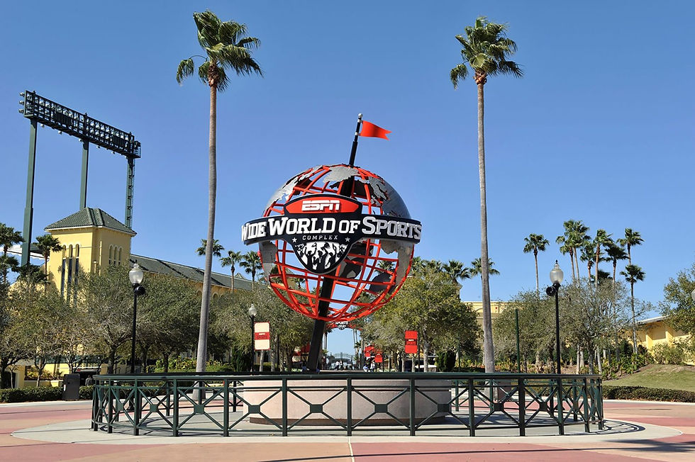 Red and silver globe with "ESPN Wide World of Sports Complex" text, surrounded by palm trees and clear blue sky, evokes excitement.