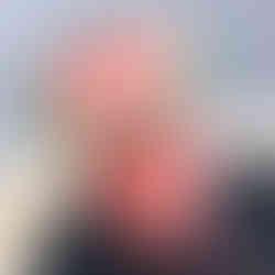 Pink slushy in a plastic cup with a green sugar rim, placed on a black slate against a blurred background, creating a fresh, summery vibe.