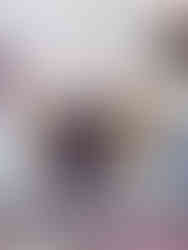 Half-eaten cupcake with white icing and blueberry filling on glass plate. Blueberries and a purple napkin in background. Cozy, sweet setting.