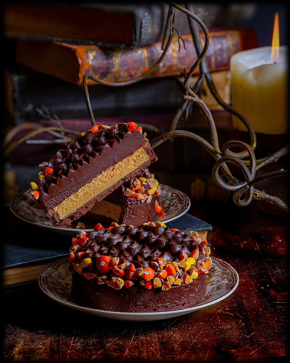 Chocolate dessert with colorful toppings on plates, set against vintage books and a lit candle in a cozy, rustic setting.