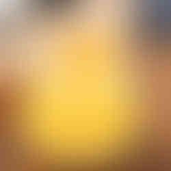 A vibrant orange cocktail in a glass on a wooden table, garnished with a slice of orange. Background is softly blurred.