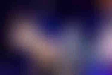 Display of intricate reindeer and rope-adorned outfit on mannequins against a deep blue backdrop, next to a gown with floral embroidery.