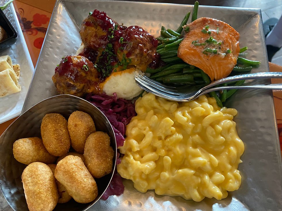 Plate with salmon, green beans, mac 'n' cheese, meatballs, mashed potatoes, and purple cabbage. Side of bread and mini corn dogs.