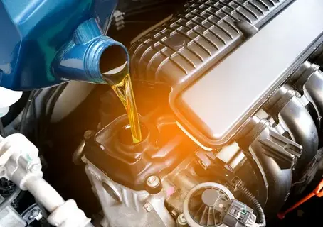 Engine oil being poured into a car engine during an oil change.