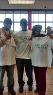 Three people holding shirts that say "GET YOUR PEOPLE UP". Get Involved.