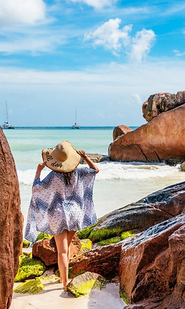 rear-view-of-young-woman-standing-on-tropical-beach-travel-summer--e1622438060210.jpg