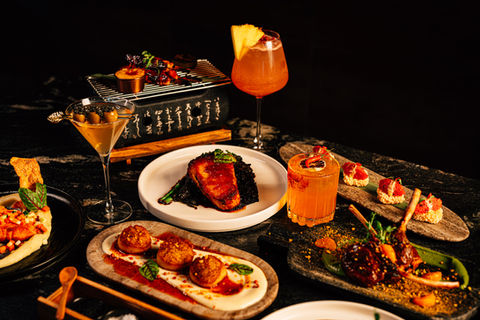 Gourmet dishes and cocktails on a dark table