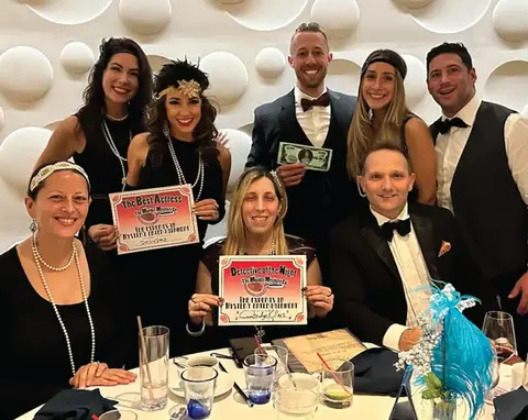 Group in 1920s attire holding certificates at an event.