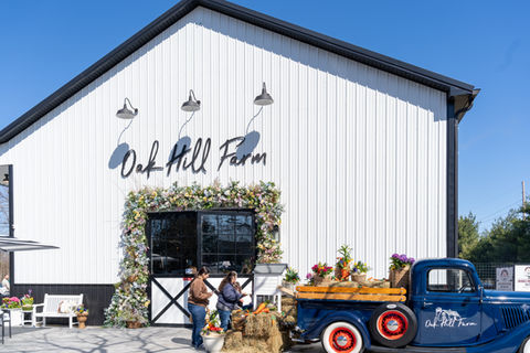 White barn with a floral-decorated doorway and the vintage blue truck loaded with pumpkins at Oak Hill Farm GEO targeted | Oak Hill Farm, Holmdel, NJ