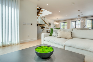 Modern minimalist open floor plan featuring sculptural fireplace, microcement flooring, and soft natural lighting throughout the space.