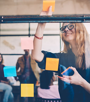 Smiling young female employee in stylish spectacles using stickers for creation strategy o
