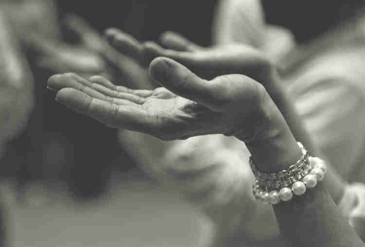 A woman holds her hands palm up and out in prayer