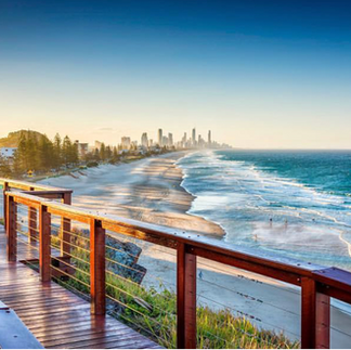Scenic view of the coastline with a boardwalk overlooking the ocean and a city skyline in the distance at Burleigh Heads, Gold Coast.