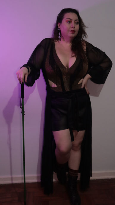 Clarice Senna posa em um vestido preto longo, segurando bengala, sorrindo para a câmera.