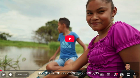 Crianças sorrindo em um barco, texto: assim dizem os velhos, os antigos, paisagem natural. Imagem do filme que Andrea Colares participou