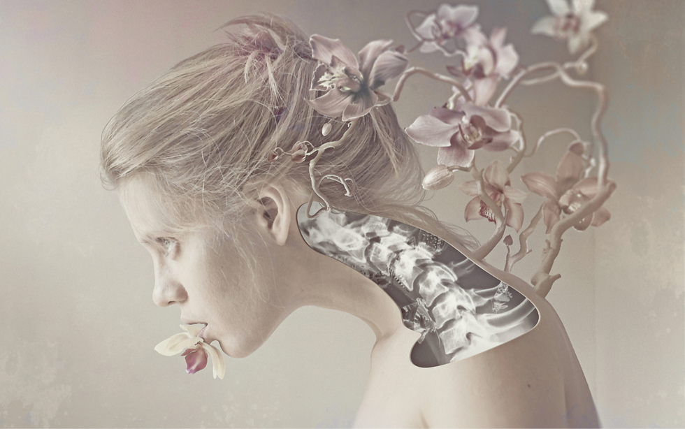 a close up image of a blonde woman with grey eyes leaning forward as lillies grow outwards from her spine.