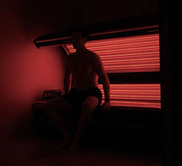 man sitting on a red light therapy pod