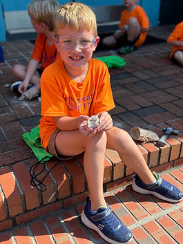Student with a field trip poses with a geode that was opened during the field trip special activity