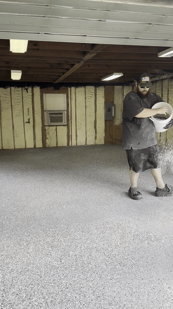 An installer broadcasts flakes on top a [olyaspartic base coat.