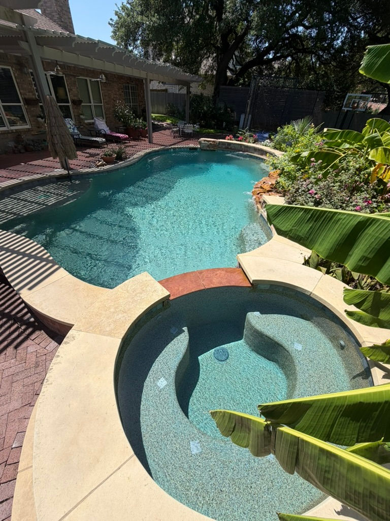 Wide landscape photo of a clean, bright backyard swimming pool with clear blue water and surrounding patio, showcasing a well-maintained residential pool.