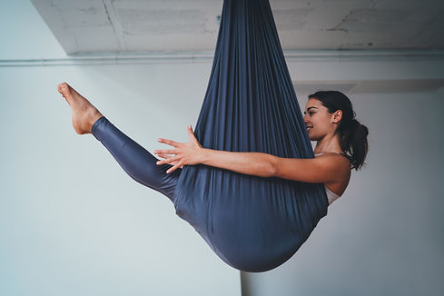 Young beautiful woman practicing aerial different inversion anti-gravity yoga with a hammo