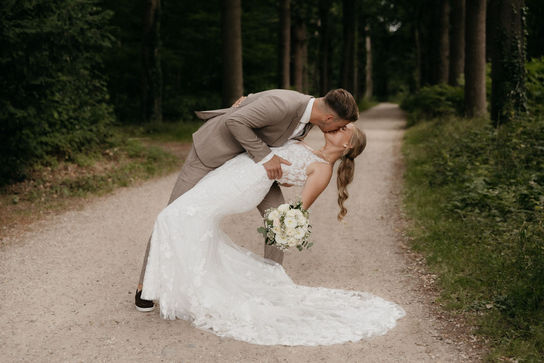 Intiem moment van bruidspaar kussend in het bos