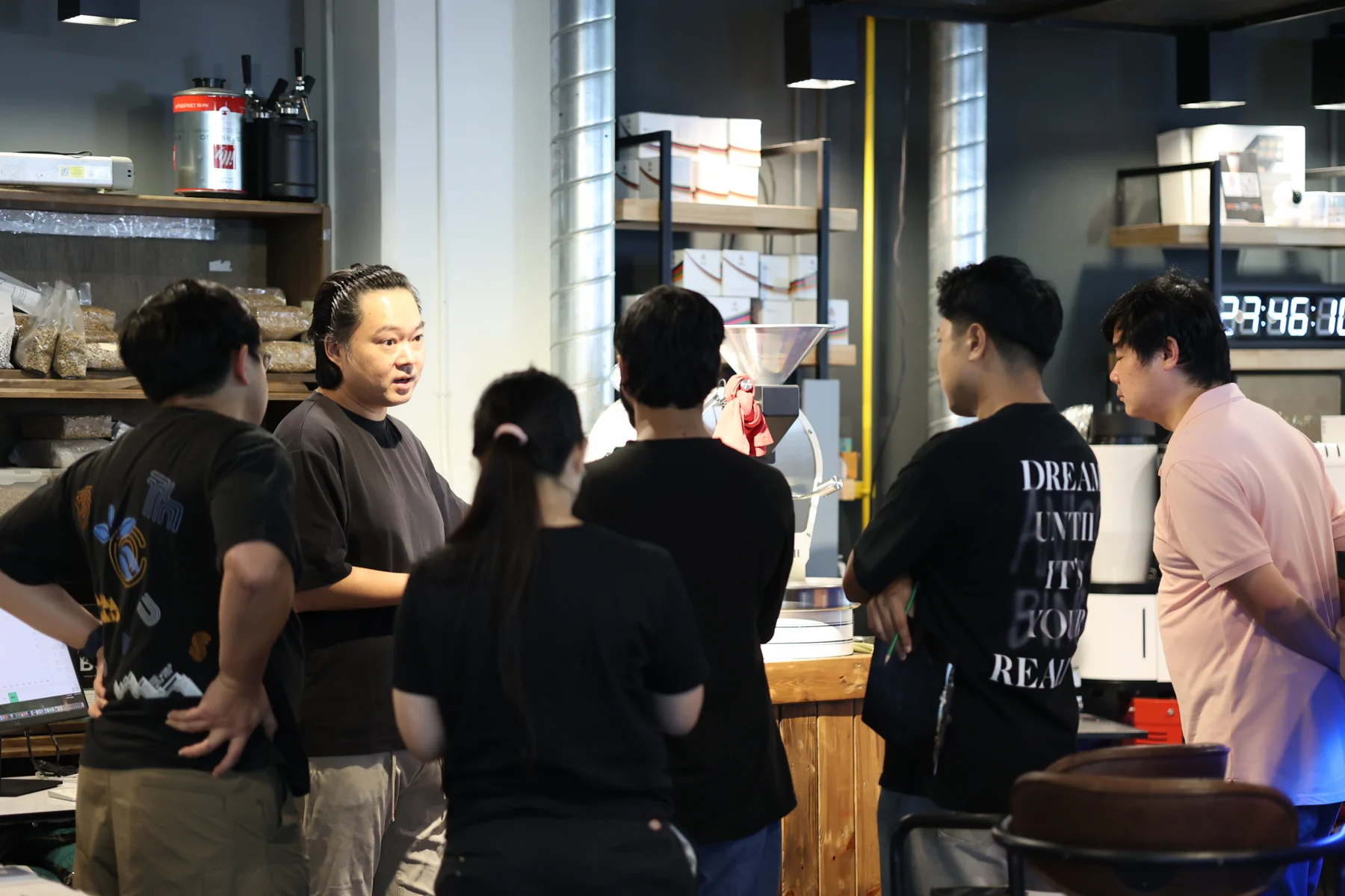 Natt teaching a group of students around a coffee roasting machine.