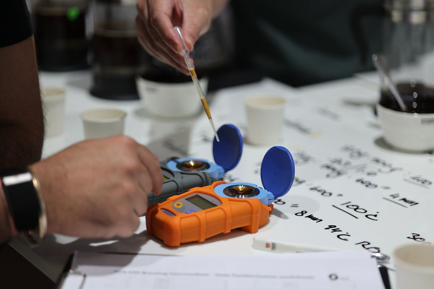 Measuring brewed coffee with refractometers beside the brewing experiment notes.