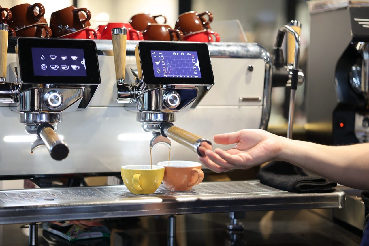 Espresso pouring into yellow and pink cups