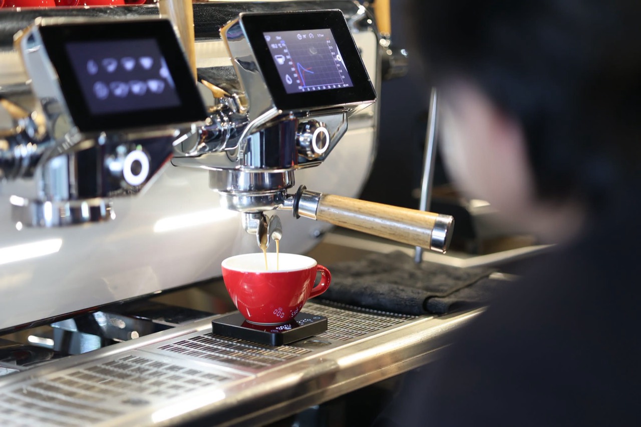 A student watching espresso extraction into a red cup