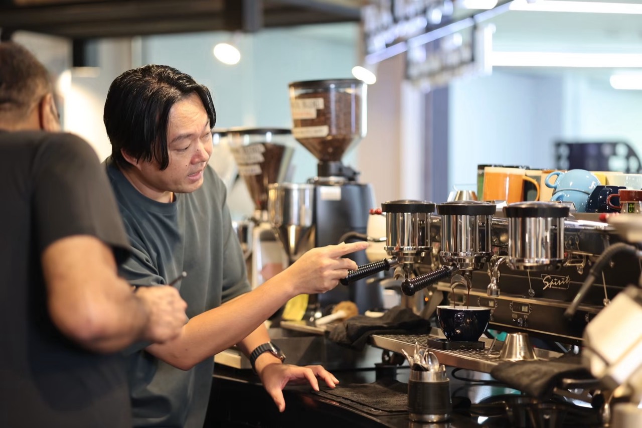 Natt demonstrating espresso machine controls to a student
