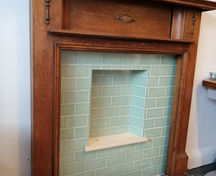 Fireplace renovation with green tile installation and a custom wooden frame, warm traditional design finish.